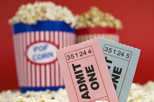 Movie Stub Two Sticking Out Of Popcorn With Two Pop Corn Bags In Background With Red Backdrop Movie Stub Two Sticking Out Of Popcorn With Two Pop Corn Bags In Background With Red Backdrop